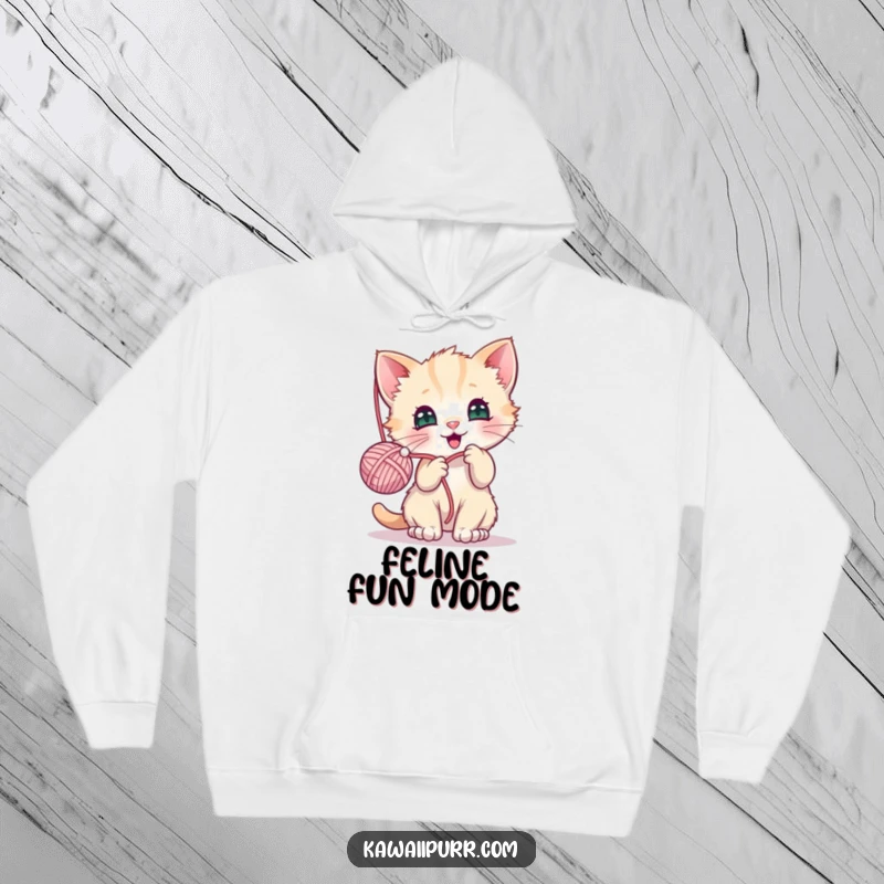 Funny hoodie with a kawaii kitten character energetically batting at a fuzzy yarn ball, radiating joy and playfulness.