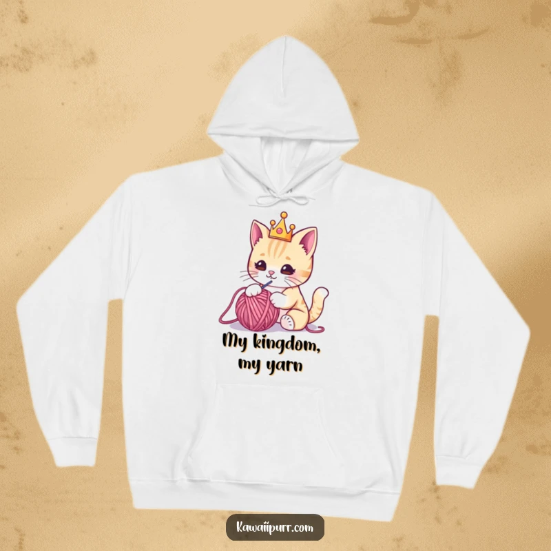 Funny hoodie with a cute kawaii cat donning a miniature crown, playfully attacking a ball of yarn, blending comfort and humor.